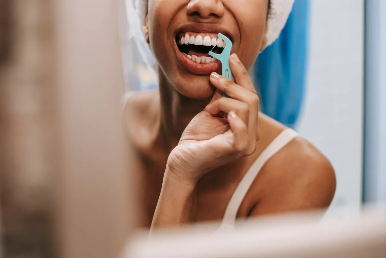 Woman using a floss pick as part of her daily oral hygiene routine.